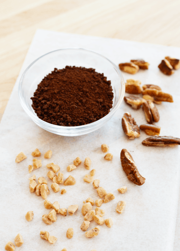 Ground coffee, pecans and toffee chips on a cutting board. 