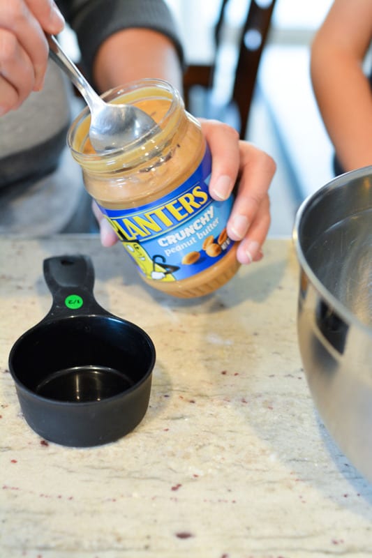 Peanut butter being spooned into a measuring cup.