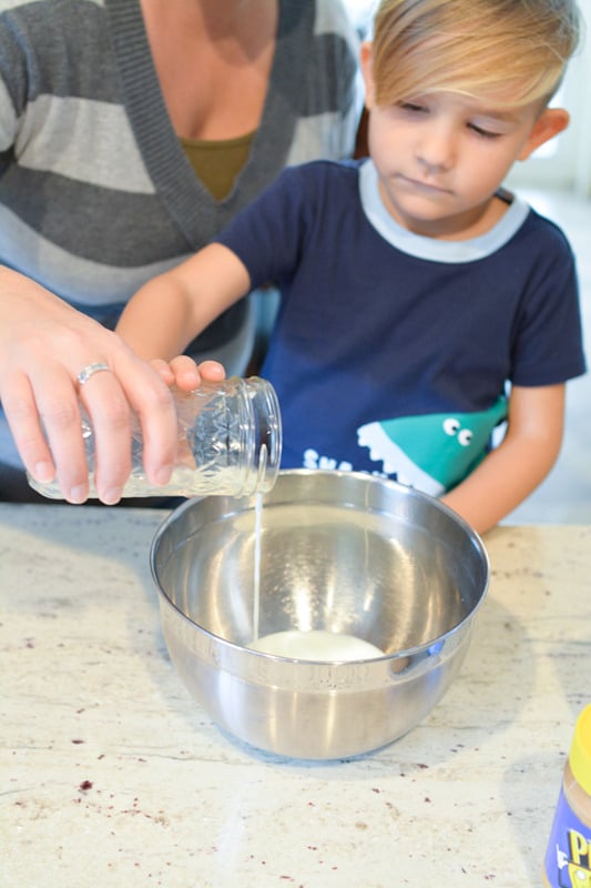Mother and child measuring ingredients into a metal bowl.