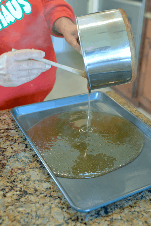 Woman pouring homemade hard candy onto a baking sheet.