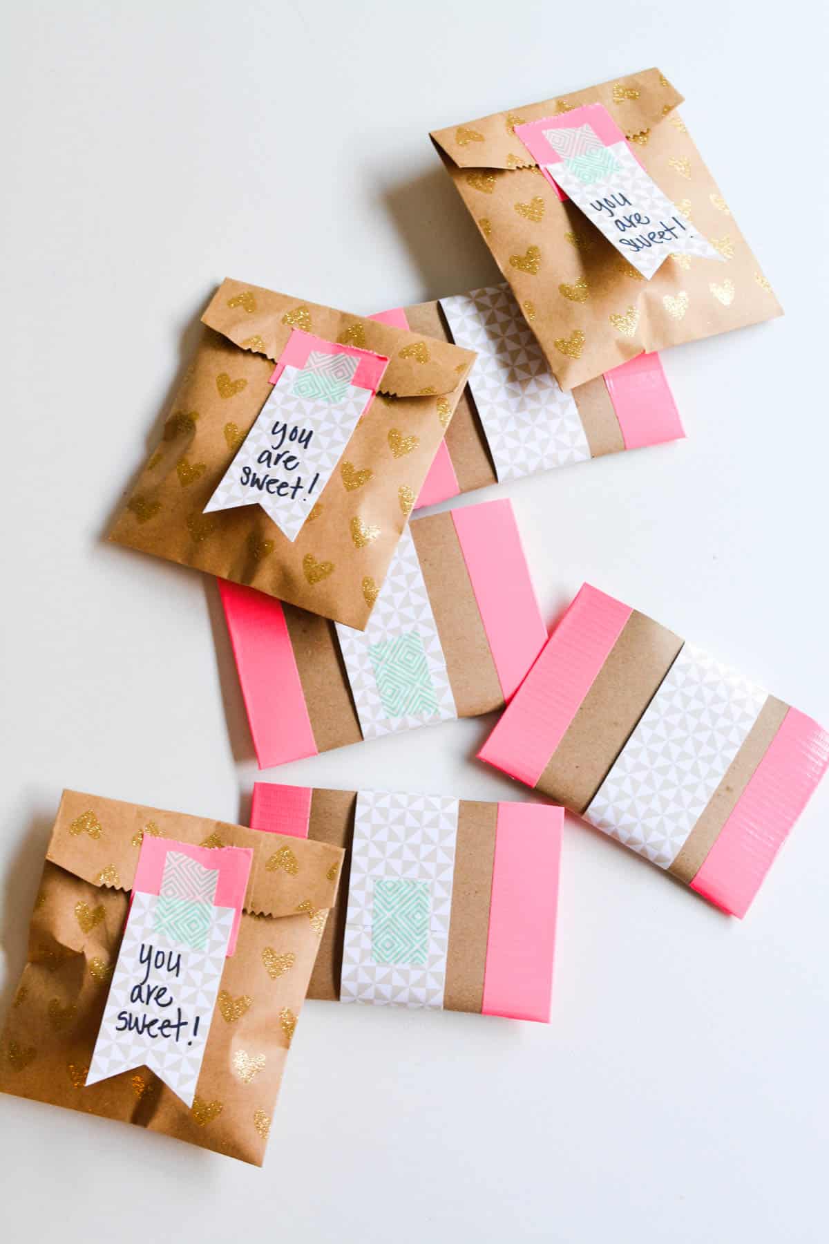 DIY gift ideas in small paper bags on a table with gift tags.