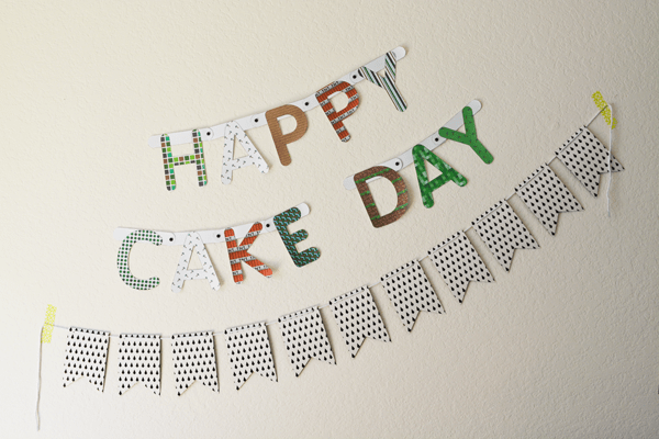 A DIY Minecraft birthday banner on a wall hanging above another banner for a party.