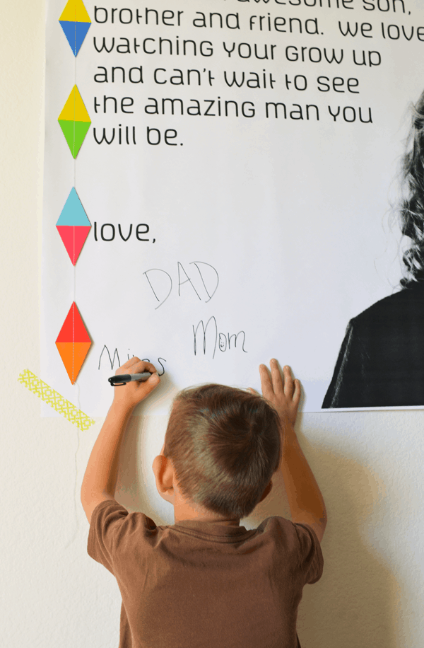 A child signing a homemade birthday poster.