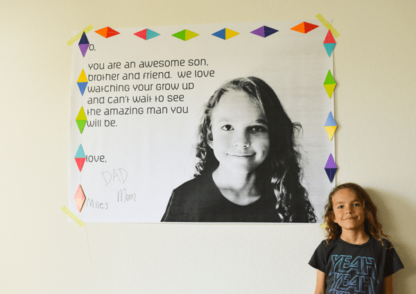 Child standing next to a DIY birthday banner.