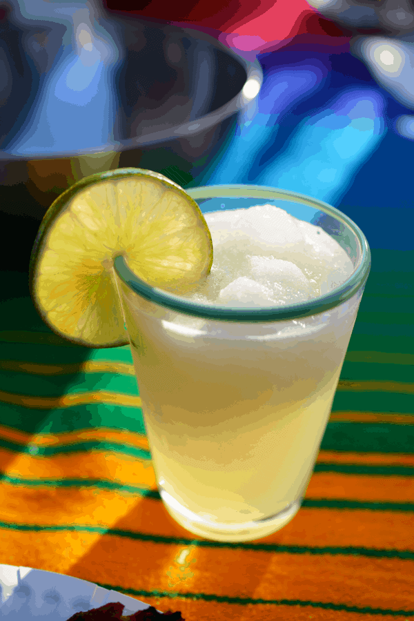 Glass of frozen margarita with a lime wheel garnish. 