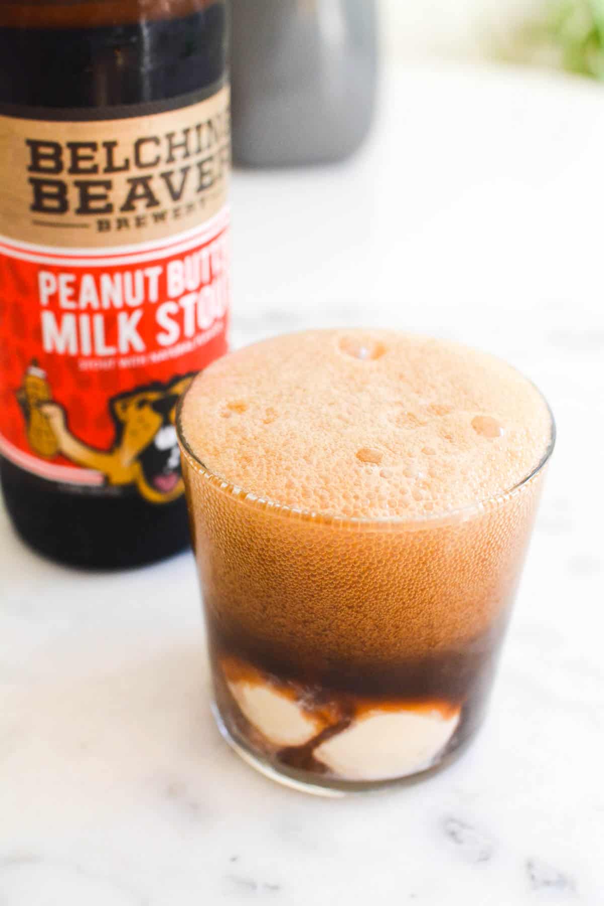 Close up of a glass holding ice cream and topped with foamy beer.
