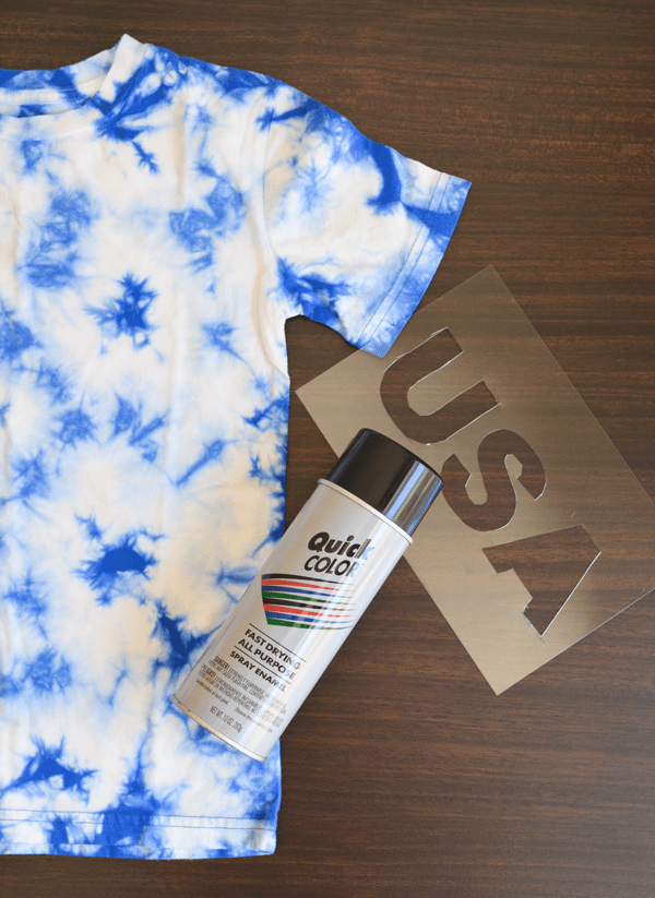 blue and white tie dye shirt on a table next to a can of spraypaint and a "usa" stencil.