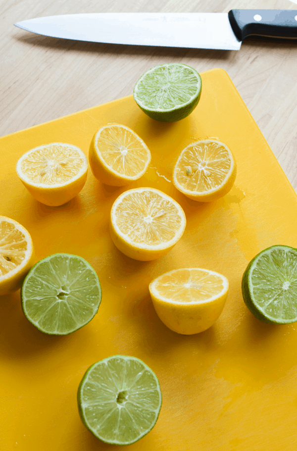 Lemons and limes cut in half on a yellow cutting board