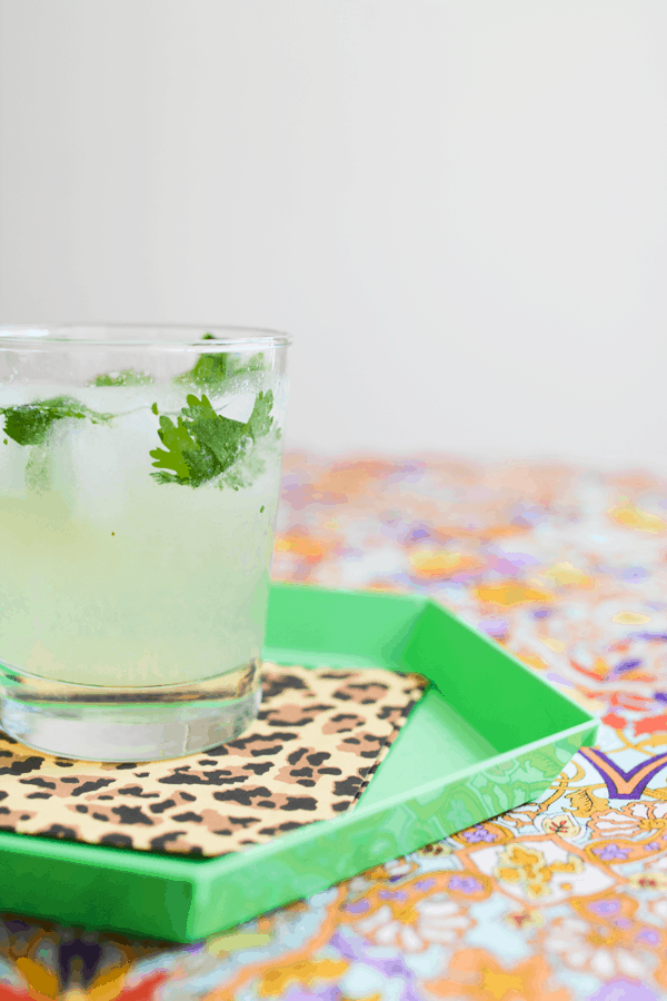 A refreshing gin cocktail in a short glass on a leopard print napkin on a green tray.