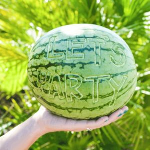 A carved watermelon held in a woman's hand.