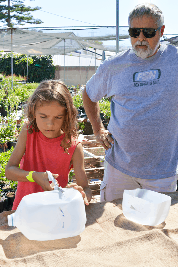 Kid cutting a plastic milk carton into a planter. 