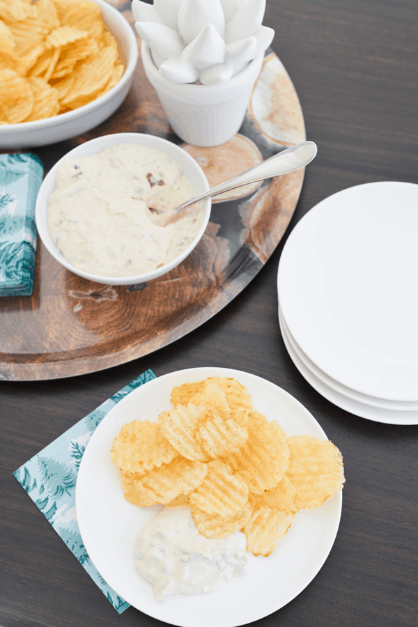 Small plates on napkin with chips and dips next to a serving tray holding the dip and chips
