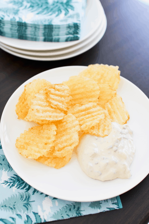 A plate with chips and dip on a table.