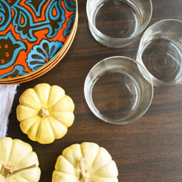 Top down image of a thanksgiving table full of plates, glasses and small pumpkins.