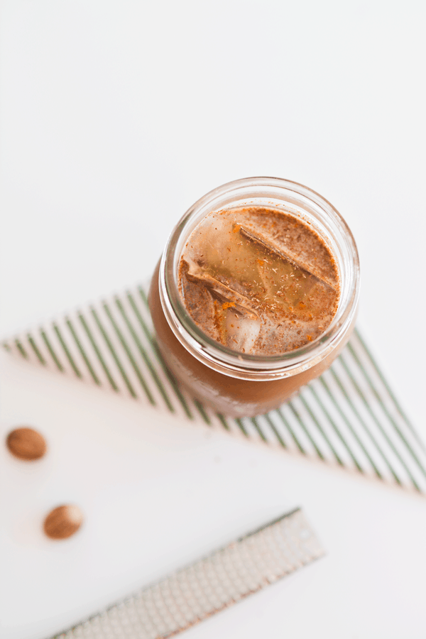 Overhead view of a jar full of iced coffee topped with spices. 