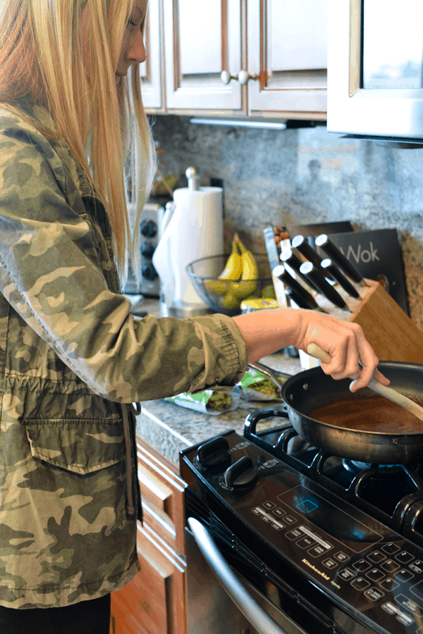 Girl at stove mixing cinnamon for glazed walnuts.