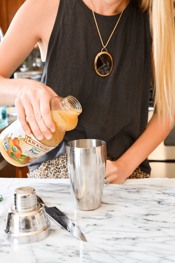 Girl pouring pear juice into a cocktail shaker. 