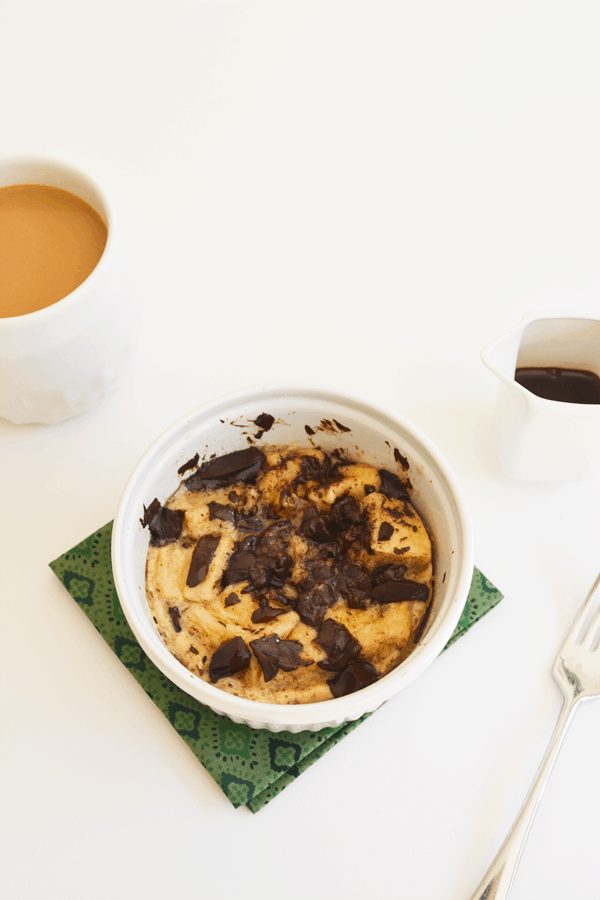 Single serve microwave chocolate bread pudding recipe on a table next to a cup of coffee and a fork