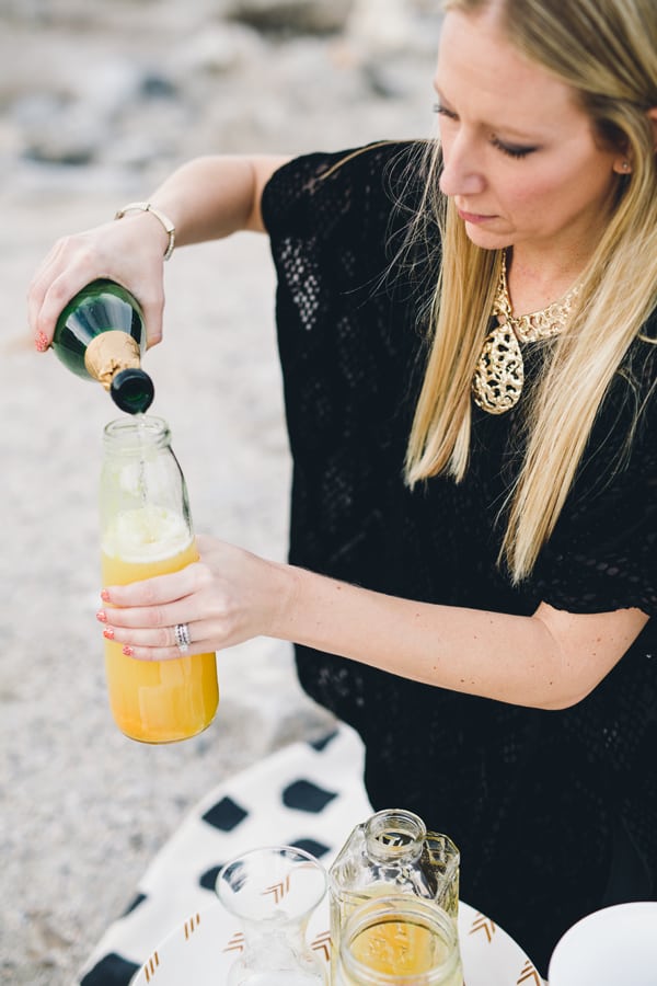 Woman adding champagne to a punch  in a glass bottle. 