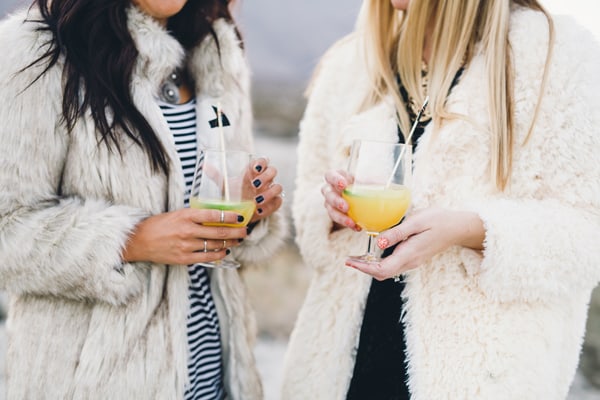 Two girls holding glasses of champagne punch outside. 