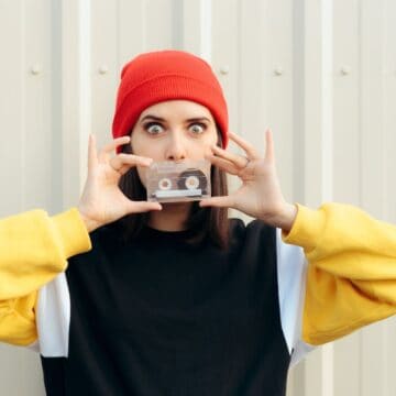 Girl dressed in 90's clothes holding a cassette tape.