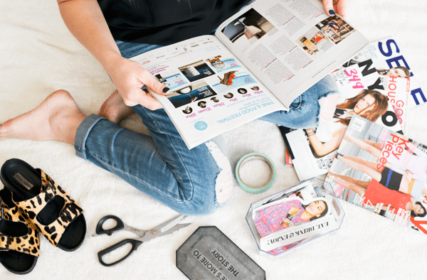 Woman flipping through a magazine with scissors next to her to make a vision box. 