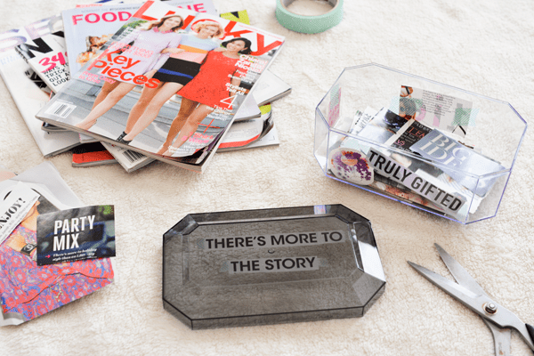 A box on the ground next to scissors and a stack of magazines.