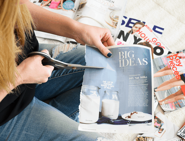 Woman cutting out words from a magazine page. 