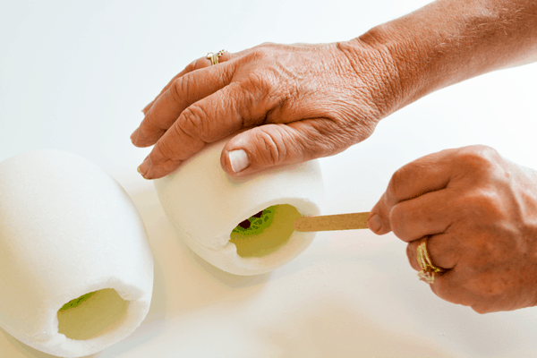 Woman filing the front of white sugar Easter eggs to smooth it out.