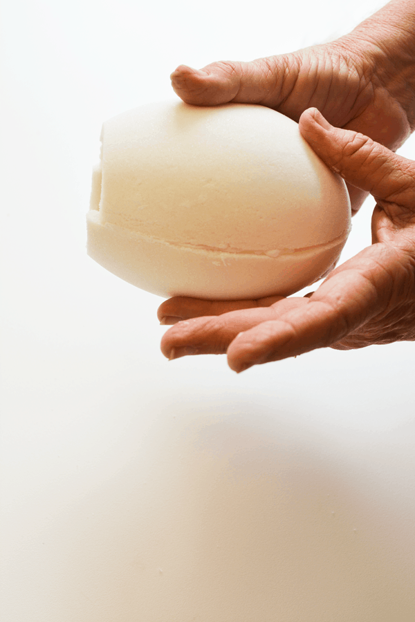 Woman holding two halves of white sugar eggs together.