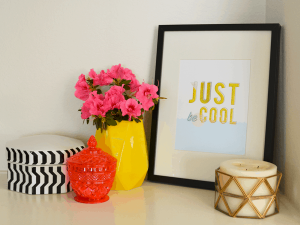 printable wall art, framed and leaning against the wall on a shelf with other home decor.