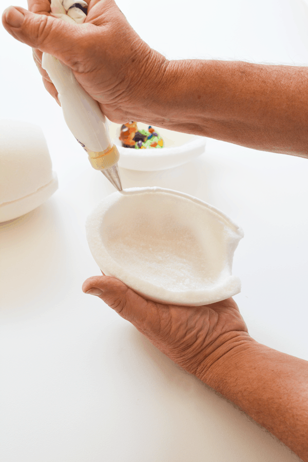 Woman putting icing on half of a white sugar Easter Egg.