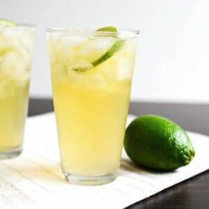 A glass filled with an easy chelada beer cocktail next to a fresh lime.