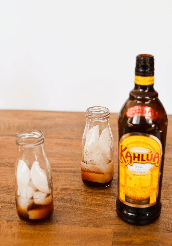 Kahlua to make a Coconut White Russian on a wood table. 