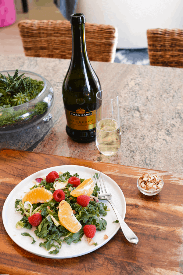 Kale salad with Prosecco vinaigrette on a white plate on a counter. 