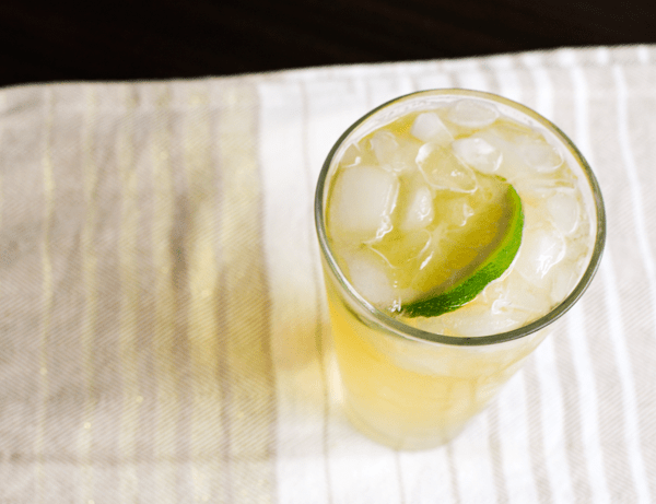 An easy chelada recipe in a glass filled with ice on top of a white and gray striped towel.