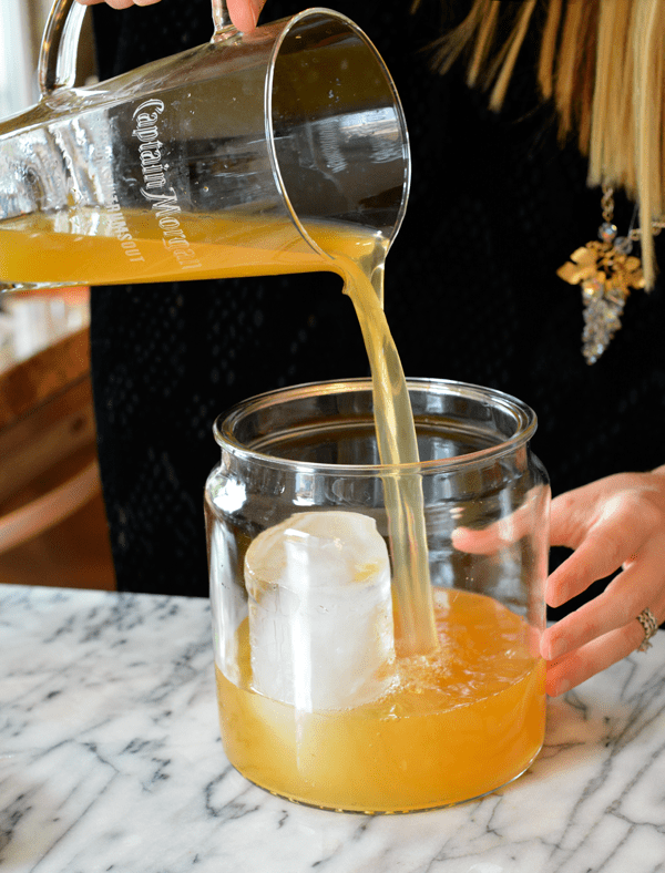 Woman pouring punch into a punch bowl with a large block of ice.