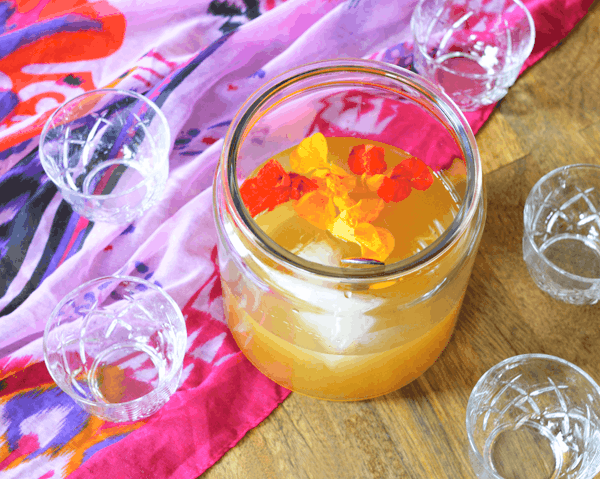 Delicious rum punch recipe with fresh citrus and vanilla bean and cinnamon simple syrup in a punch bowl surrounded by punch glasses.
