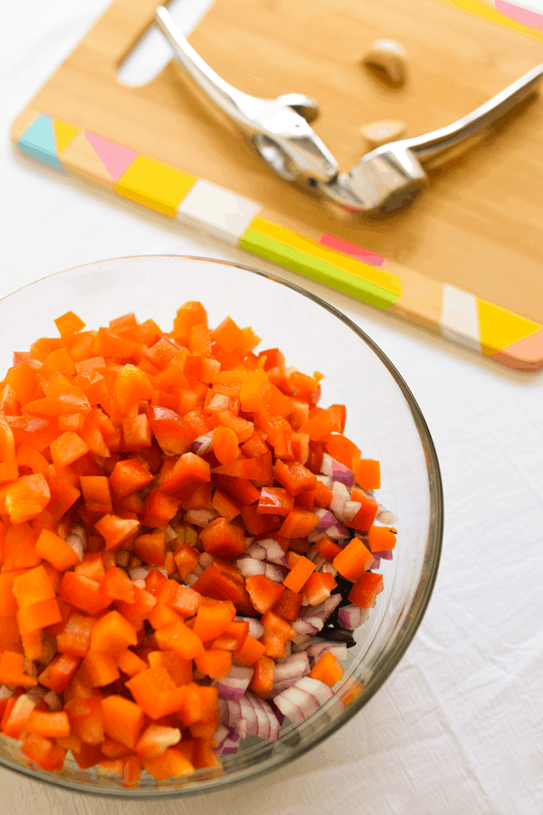 A bowl with ingredients for a Black Bean Salad with fresh onion and bell pepper.