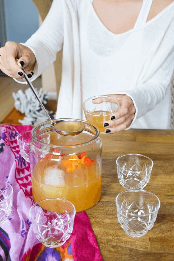 Woman ladeling tiki rum punch into a glass. 
