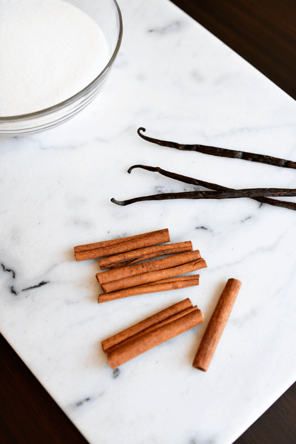 Cinnamon sticks and vanilla beans on a cutting board.