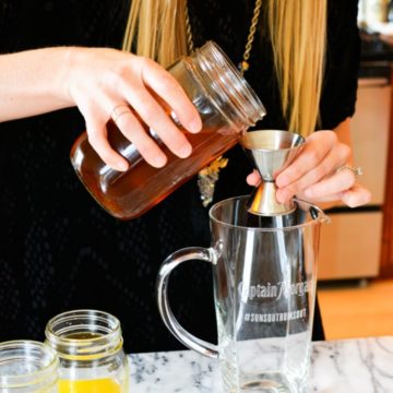 Pouring vanilla simple syrup into a pitcher.