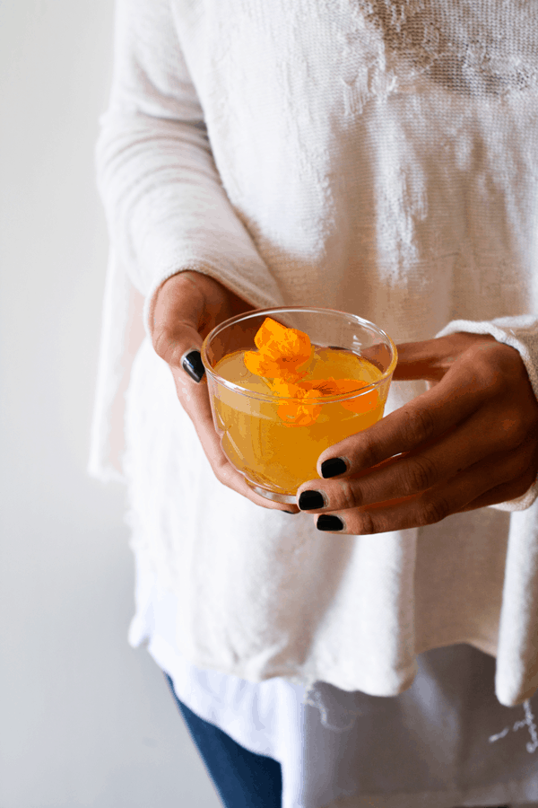 Woman holding a glass of rum punch topped with a flower.