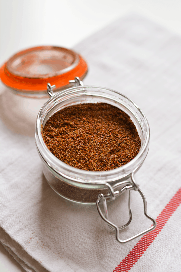 Close up of taco seasoning in a glass canister. 