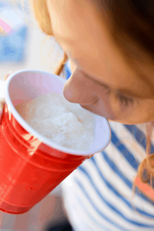 Child drinking a Pina Colada mocktail slushy out of a red solo cup.