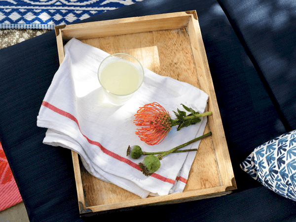 A wooden tray on a cushion with a towel and a cup holding a Corpse Reviver cocktail. 