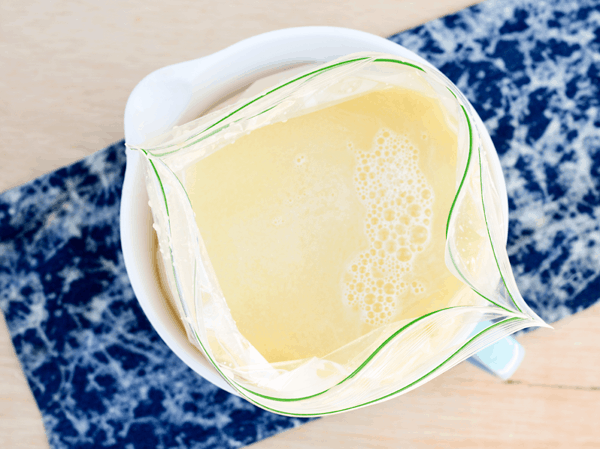 Frozen pina colada slush being poured into a freezer bag.