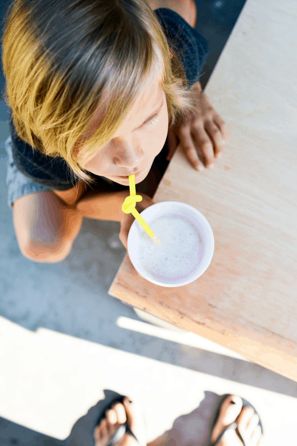 Boy drinking a Fizzy Pina Colada Slush out of a solo cup with a yellow curly straw.