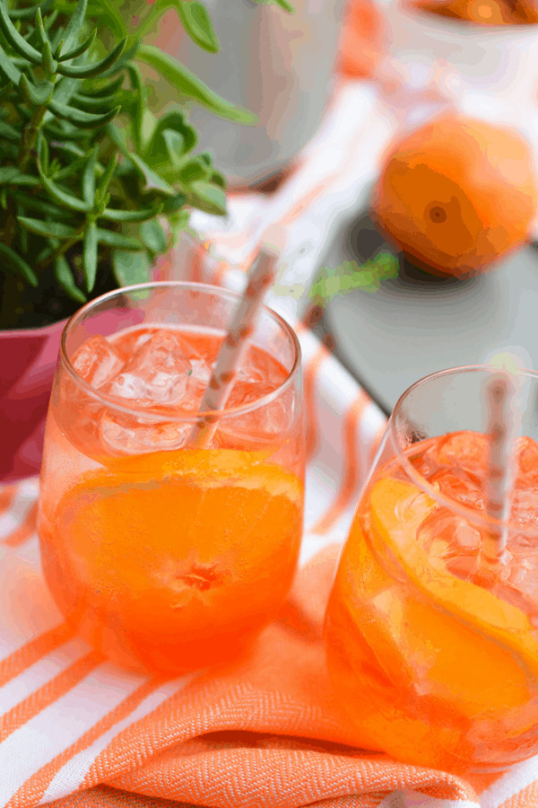 Stemless wine glasses filled with Aperol Spritz on a table.