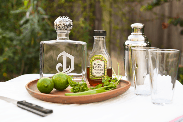 Serrano Margarita ingredients on a white table outdoors.